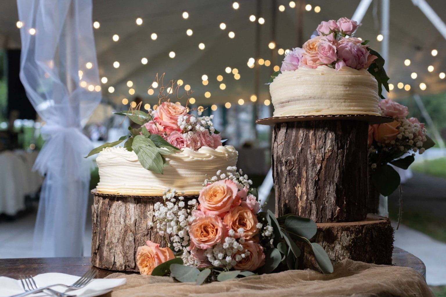 Three wedding cakes are sitting on wooden stump slices on a table.