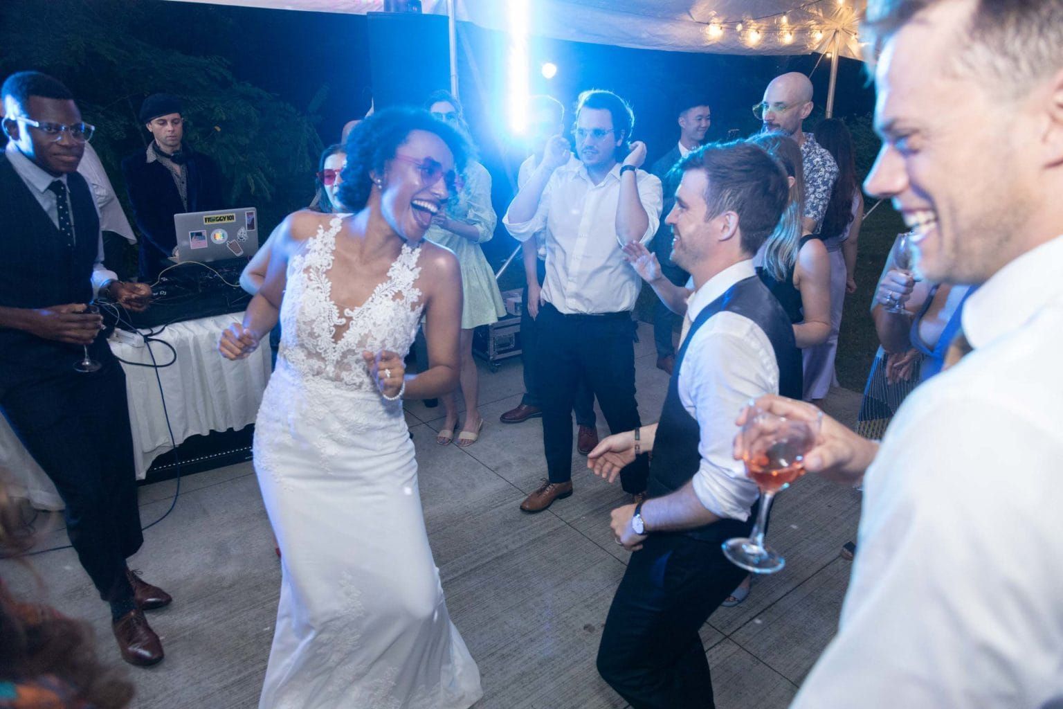 A bride and groom are dancing at a wedding reception with their guests.