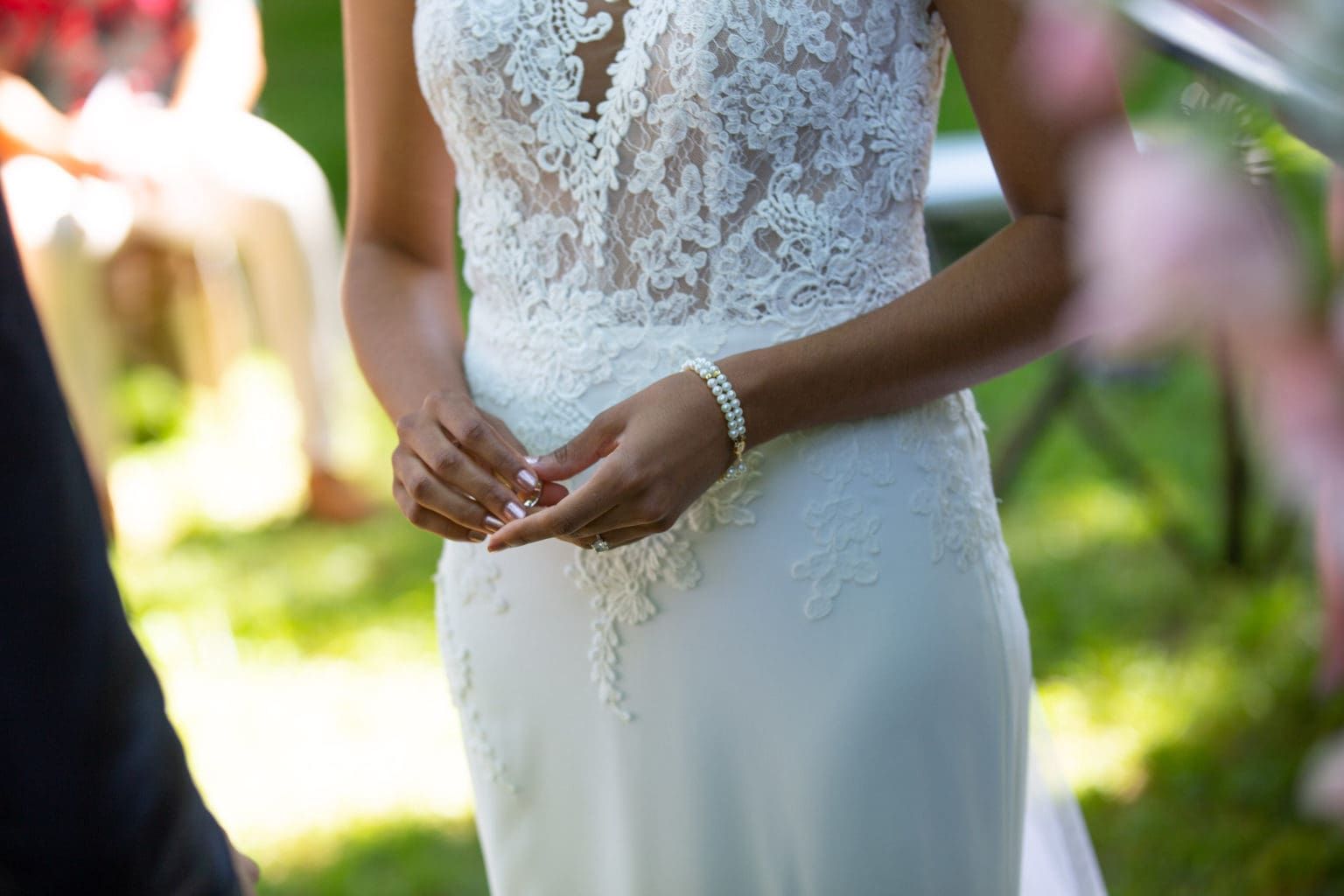 A close up of a woman in a wedding dress holding her hands together.
