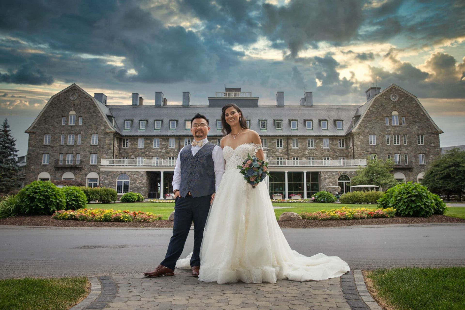 A bride and groom are posing for a picture in front of a large building.