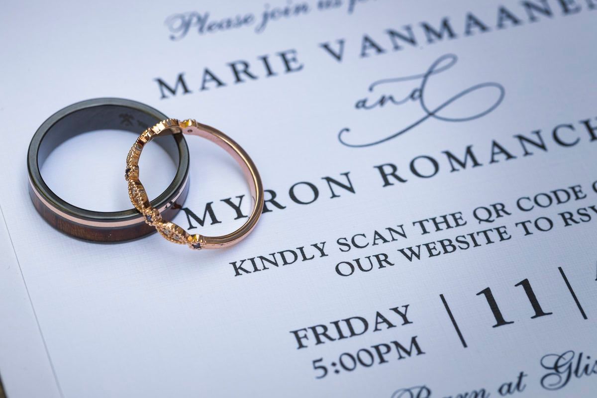 A couple of wedding rings on top of a wedding invitation