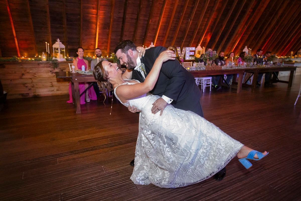 A bride and groom are dancing at their wedding reception in a barn.