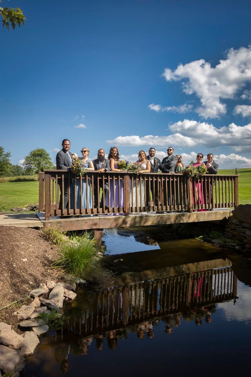 A group of people are standing on a bridge over a body of water.
