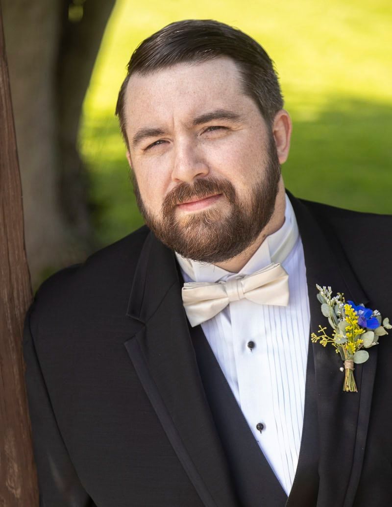 A man with a beard is wearing a tuxedo and bow tie.
