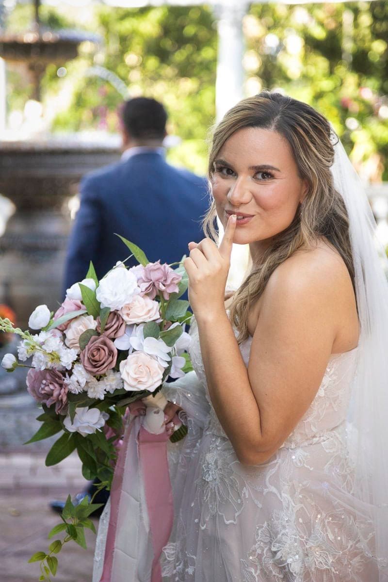 A bride is holding a bouquet of flowers and licking her lips.