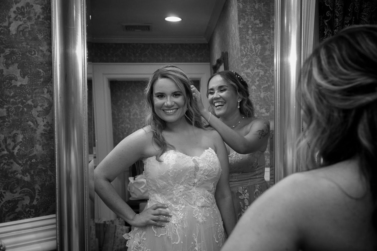 A woman in a wedding dress is looking at herself in a mirror.