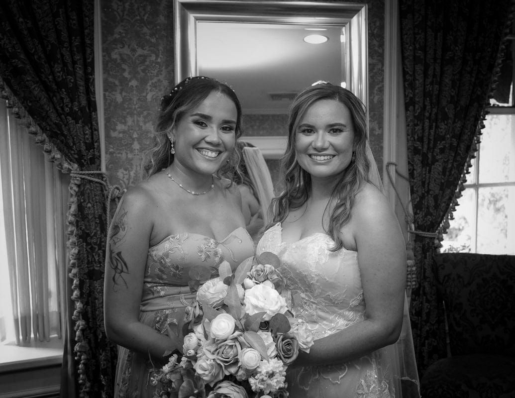 A bride and her bridesmaid are posing for a black and white photo.