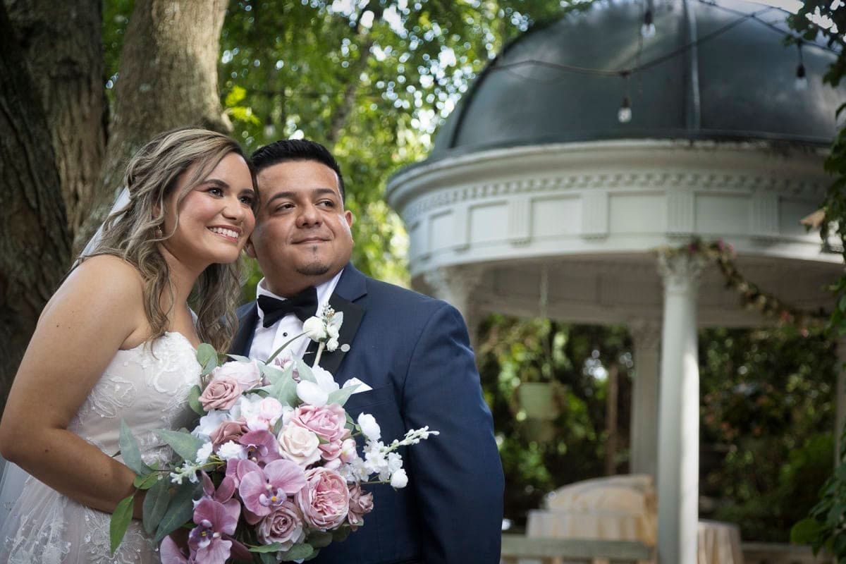 A bride and groom are posing for a picture in front of a gazebo.