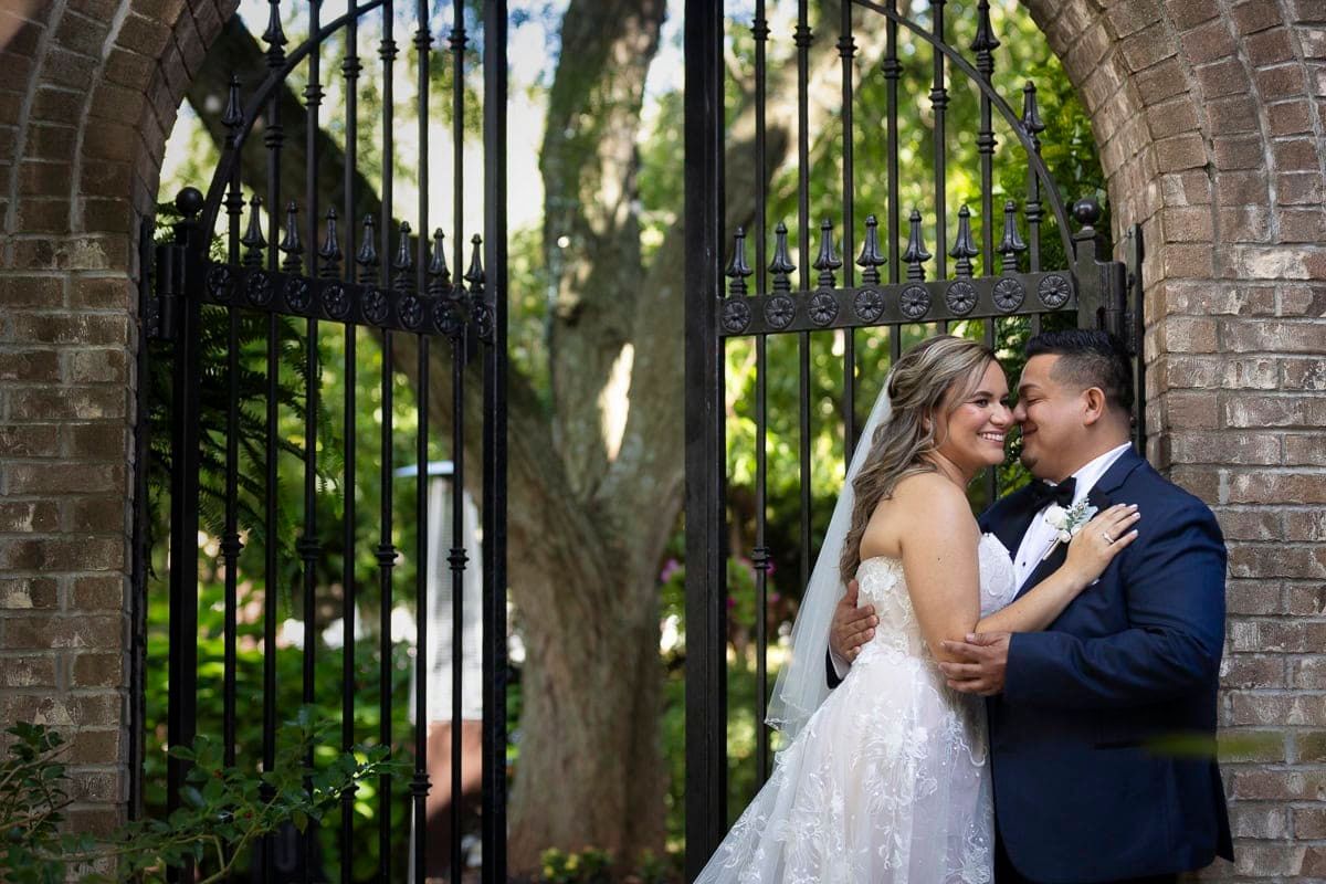 A bride and groom are posing for a picture in front of a gate.