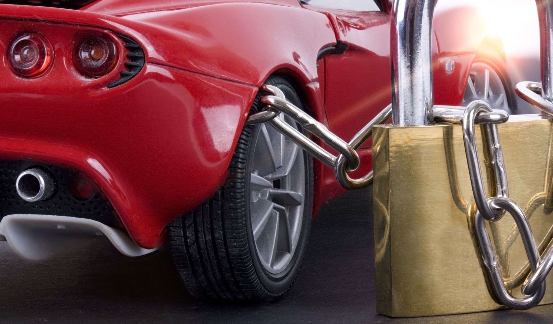 Red car wheel chained to a padlock, for security.