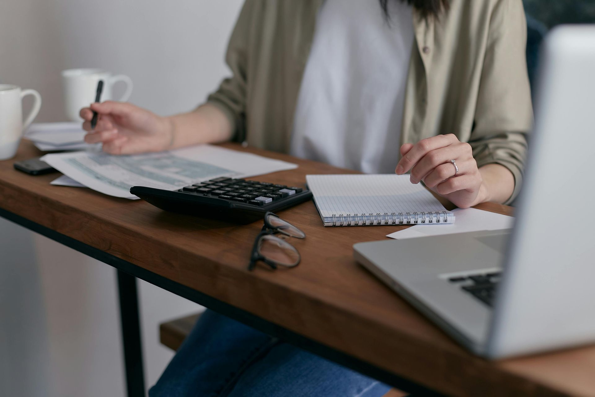 A woman is sitting at a table with a laptop and a calculator.