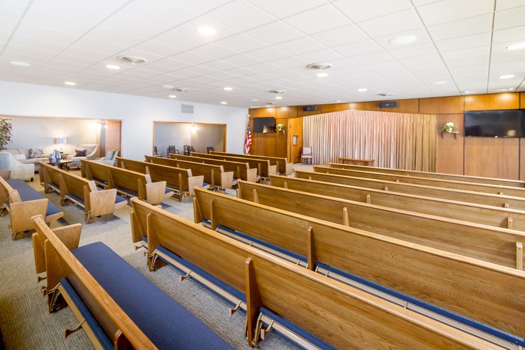 A church filled with rows of wooden benches and chairs.