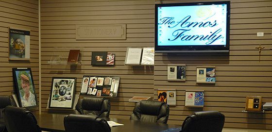 A conference room with a tv on the wall that says the amos family