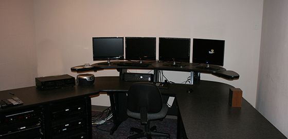 A computer desk with four monitors and a laptop on it