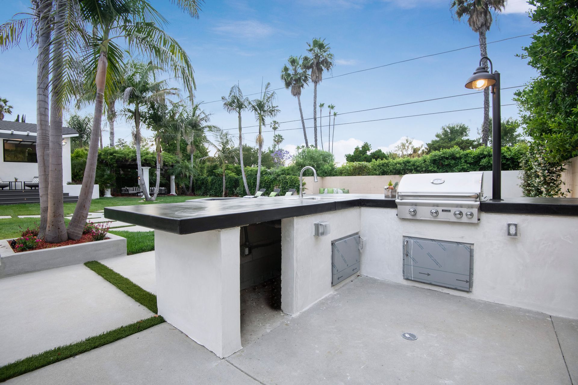 A large outdoor kitchen with a grill and a wooden fence.
