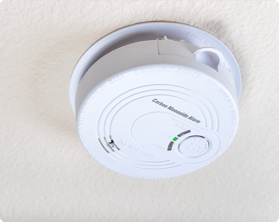 A white smoke detector with a green light on it