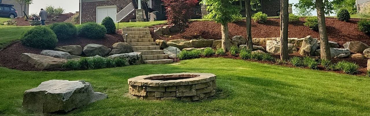 A fire pit is sitting in the middle of a lush green lawn.