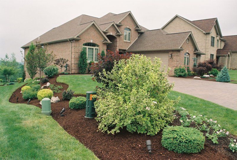 A large house with a lot of plants in front of it
