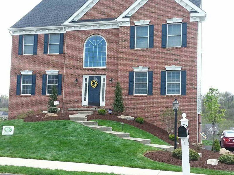 A large brick house with blue shutters and a mailbox