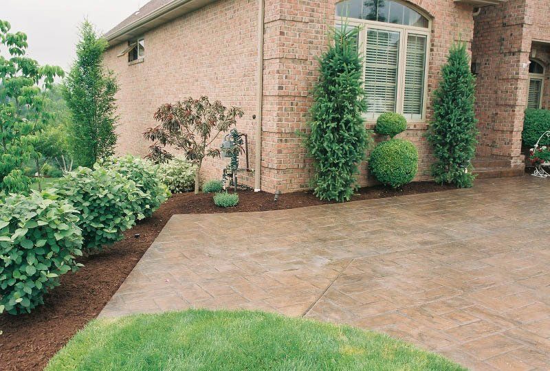 A brick house with a concrete driveway in front of it
