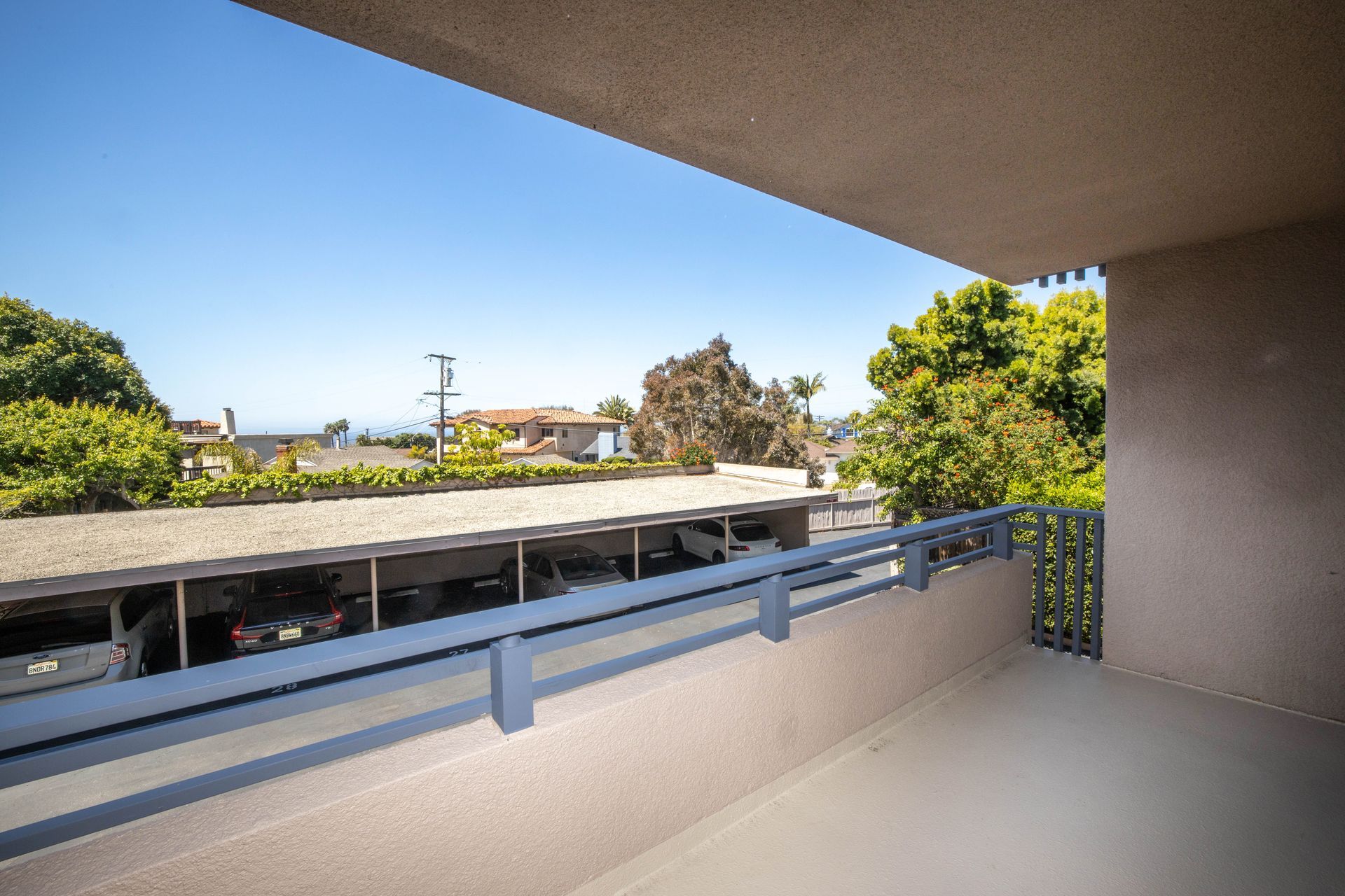 Balcony overlooking rooftops and trees under a clear blue sky