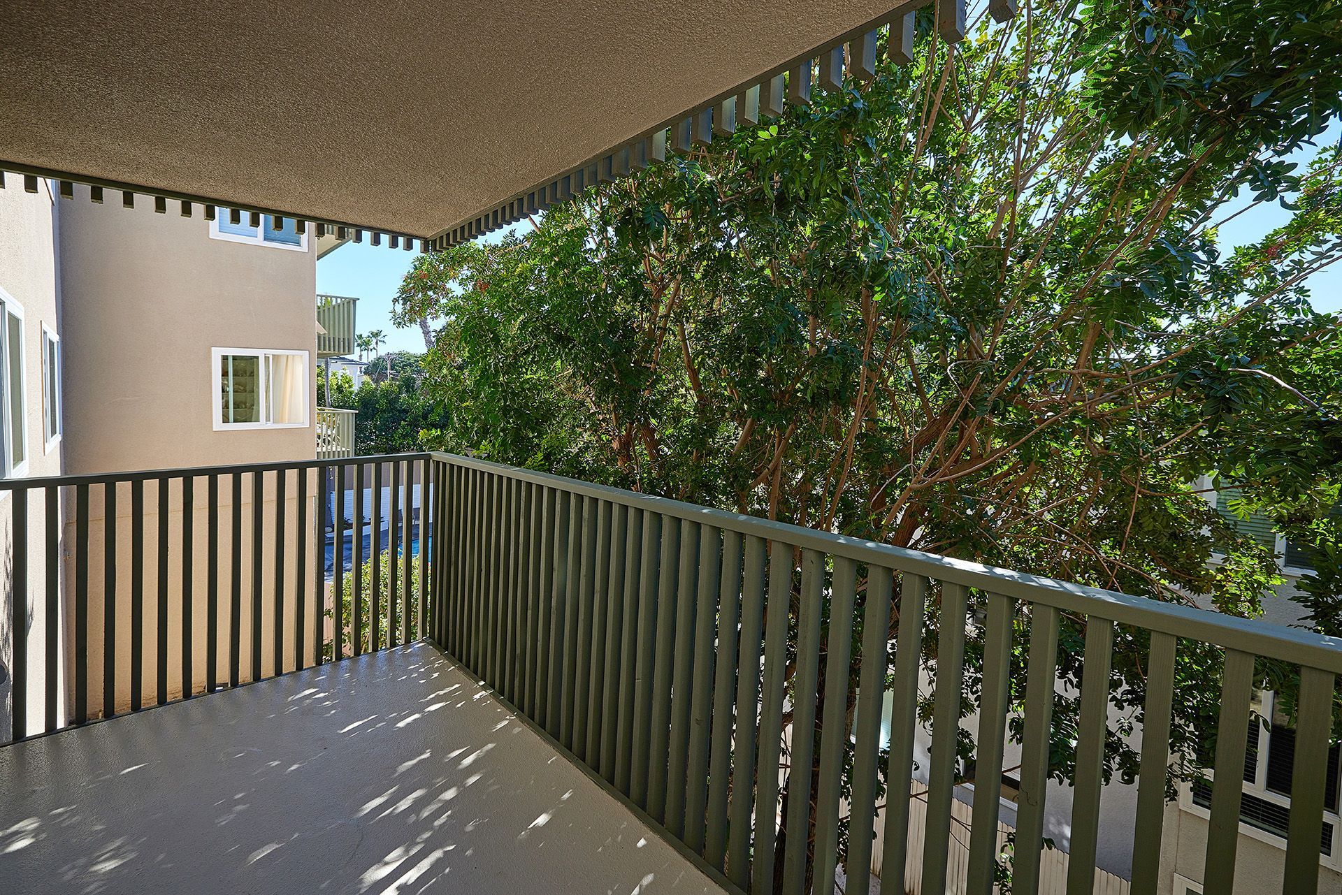 Covered apartment balcony with striped railing and trees in the view