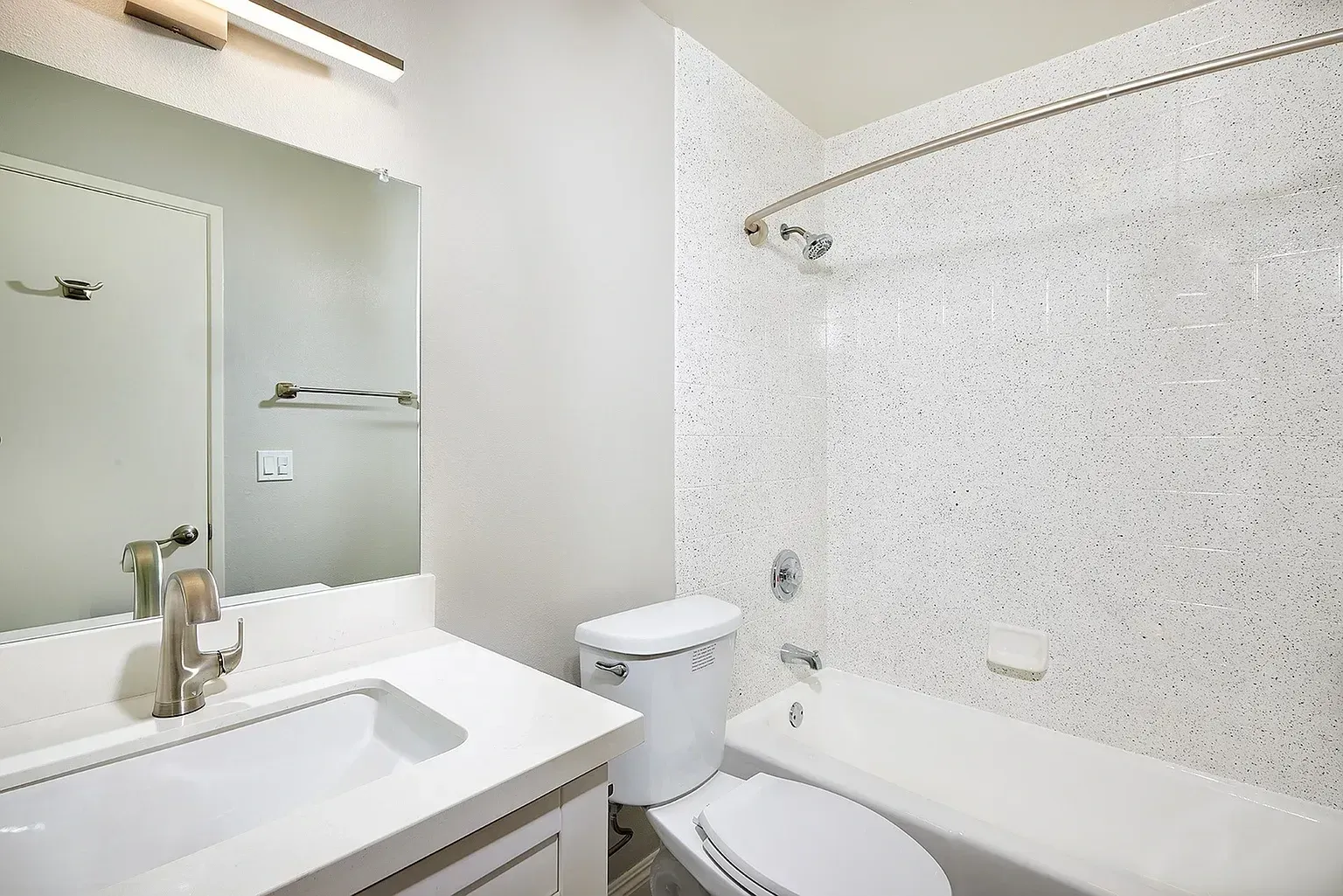 Bright modern bathroom with a sink, mirror, toilet, and bathtub