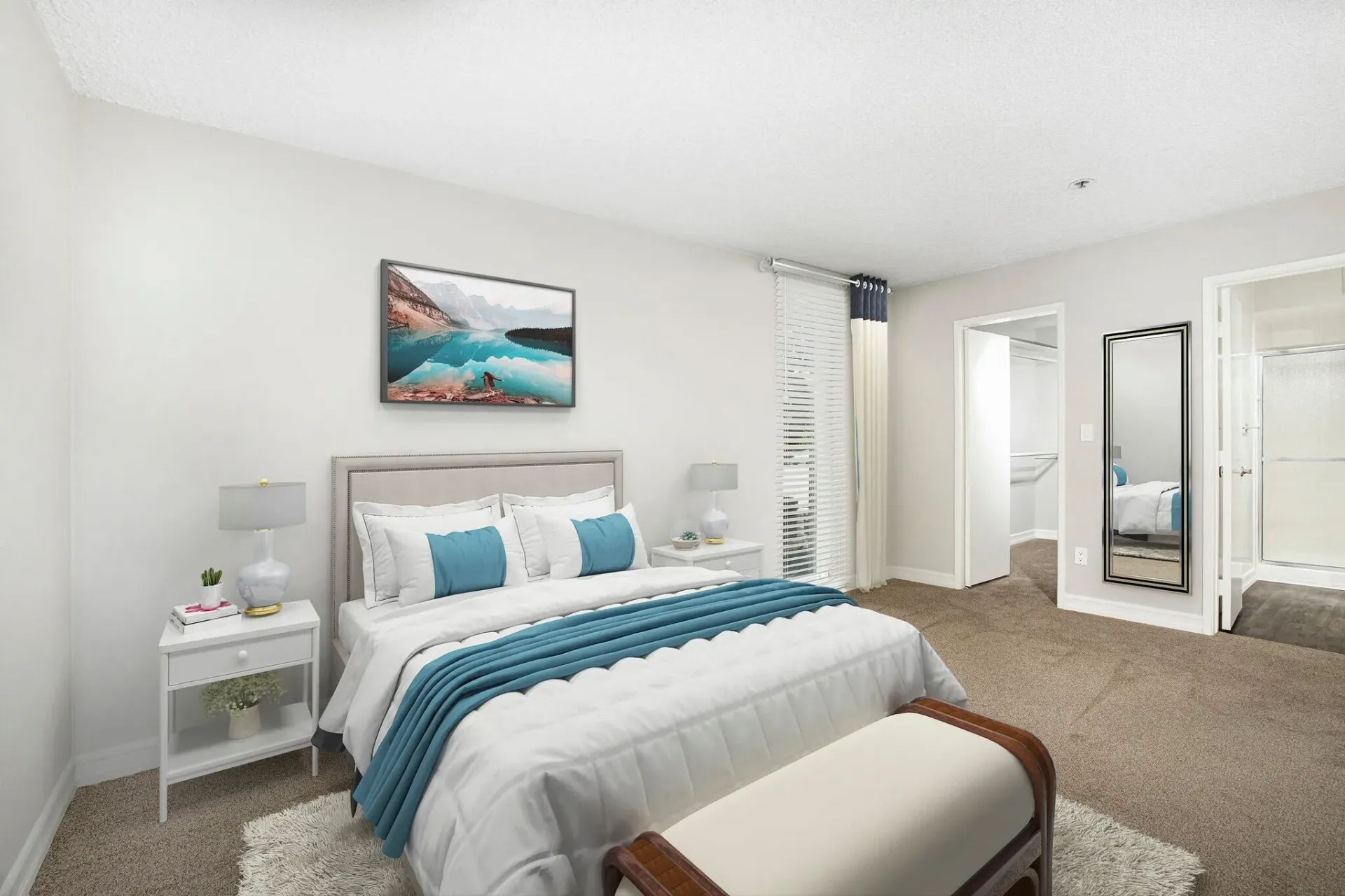 Bright bedroom with a white bed, teal accents, mirrored closet doors, and beige carpet