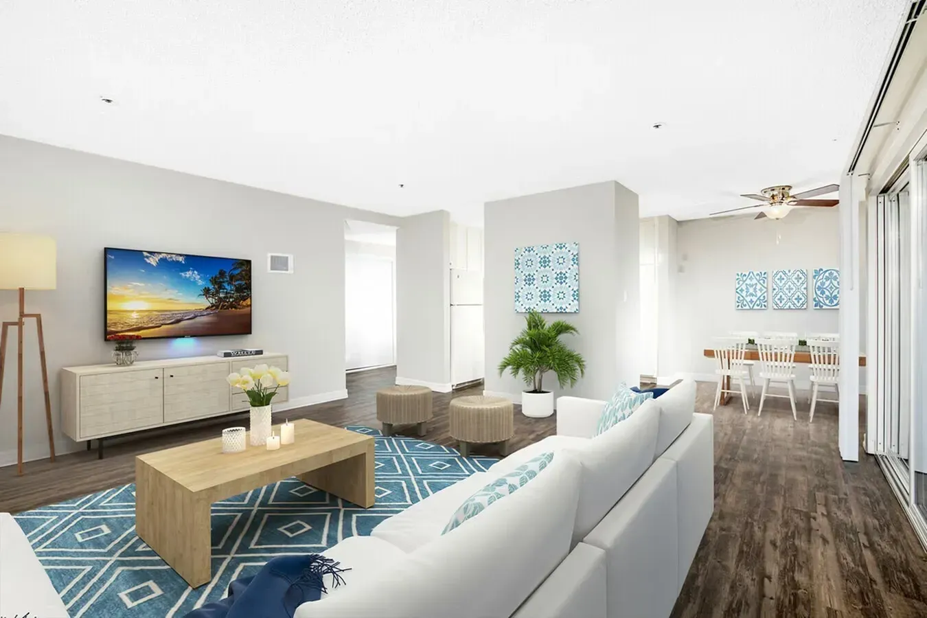 Modern living room with white sofas, wood coffee tables, blue rug, TV, and dining area