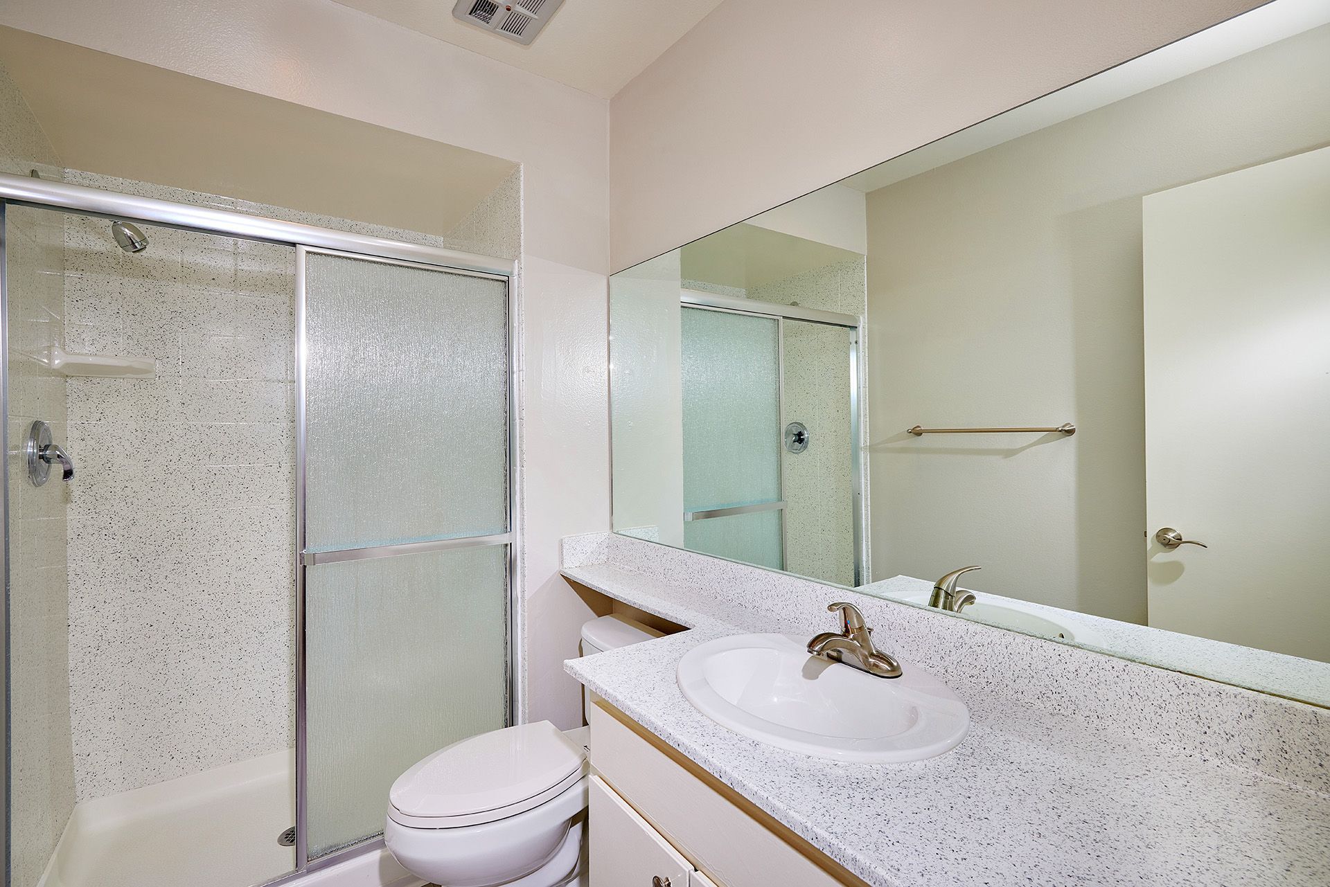 Bright bathroom with glass shower, toilet, and vanity mirror under soft lighting