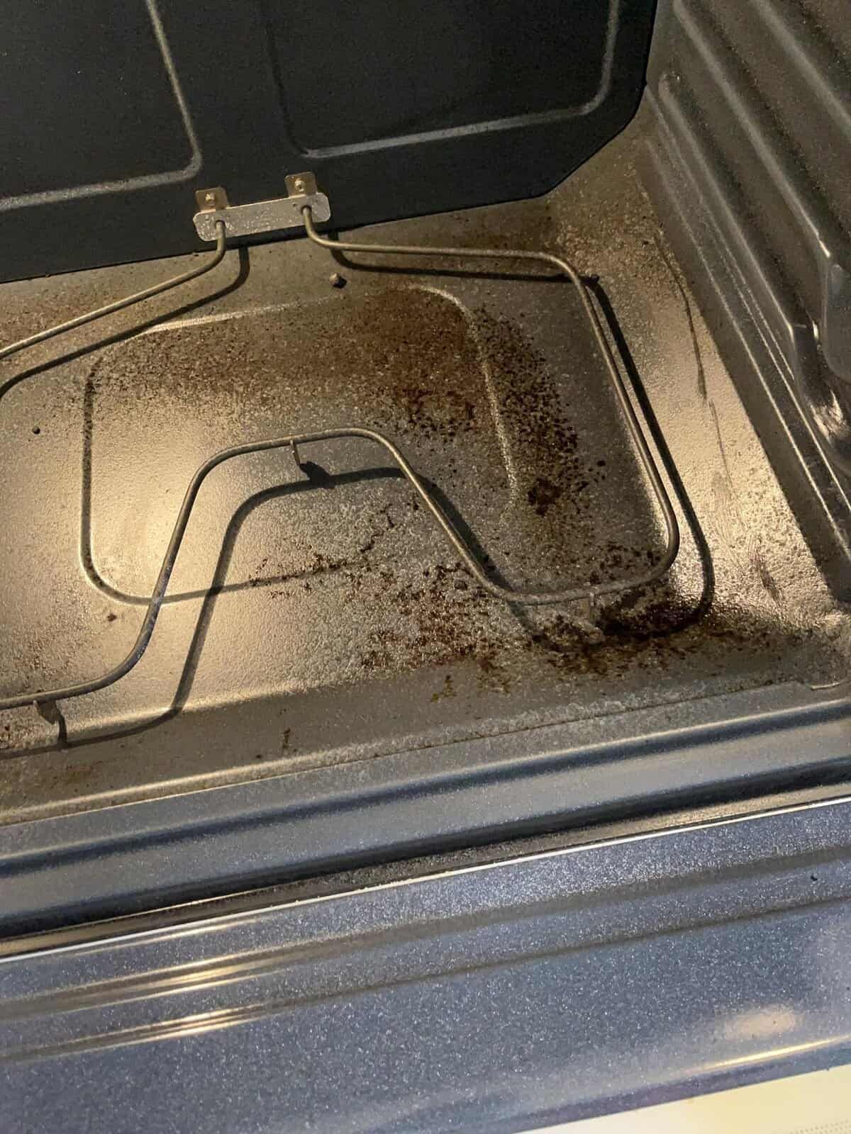 Dirty oven interior with heating element and splattered food residue.