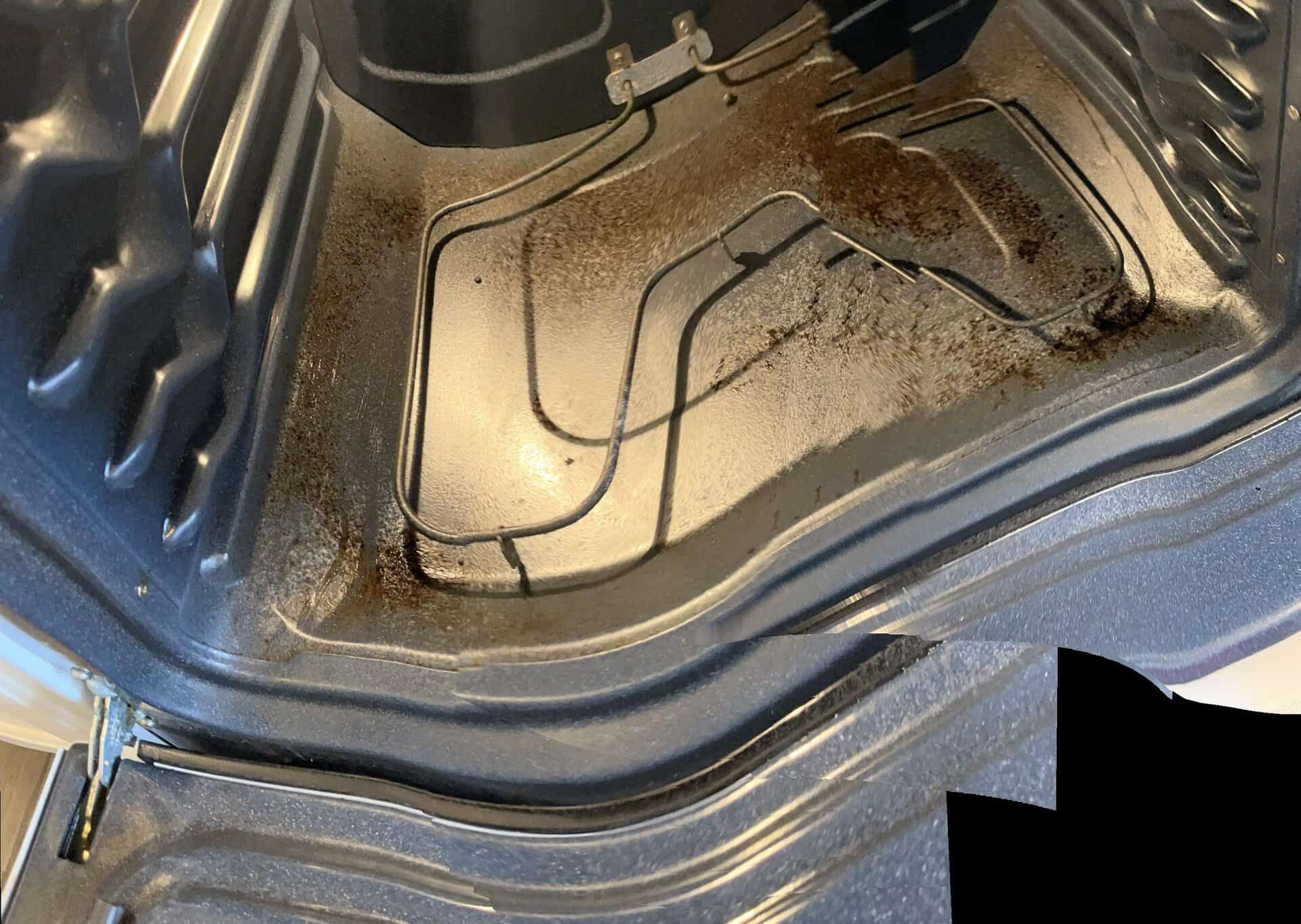 Dirty oven interior with burnt food residue on heating element and bottom.