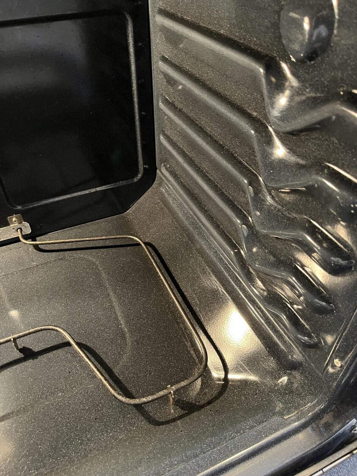 Interior of a black oven. A heating element is visible on the bottom.