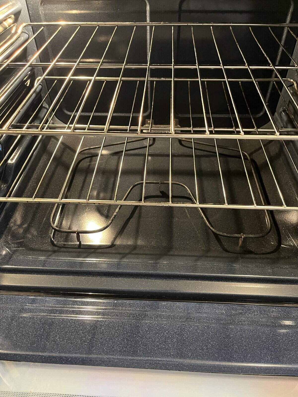 An empty oven with two racks inside. The lower heating element is visible.
