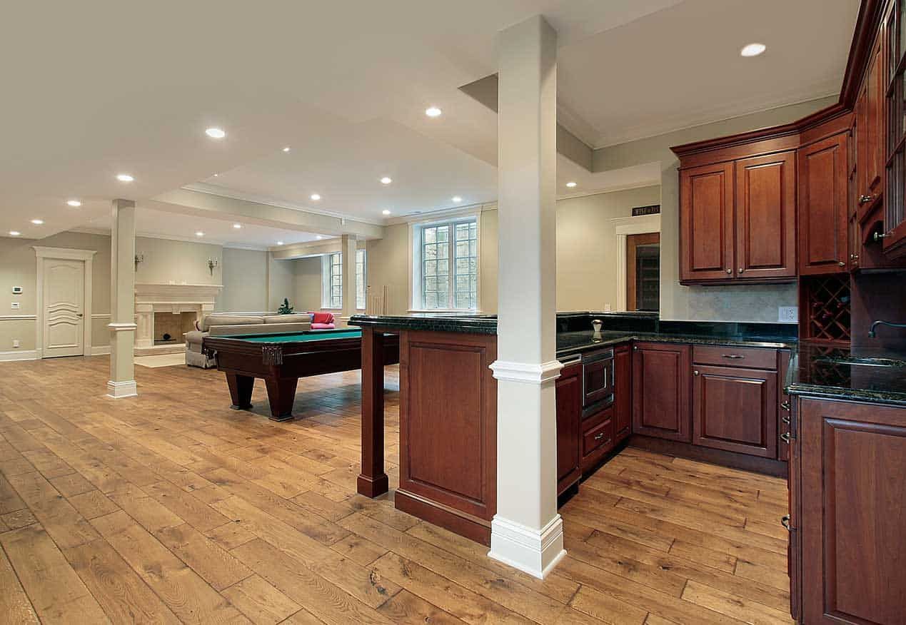 Spacious finished basement with a pool table, kitchenette, and hardwood floors.