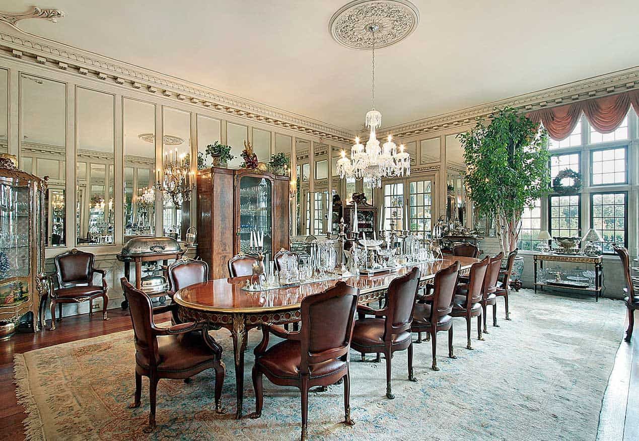 Elegant dining room with large oval table, chairs, chandelier, and mirrored walls.