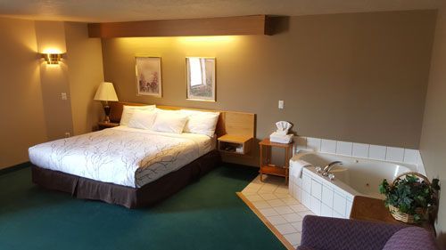 A hotel room with a king size bed and a jacuzzi tub.