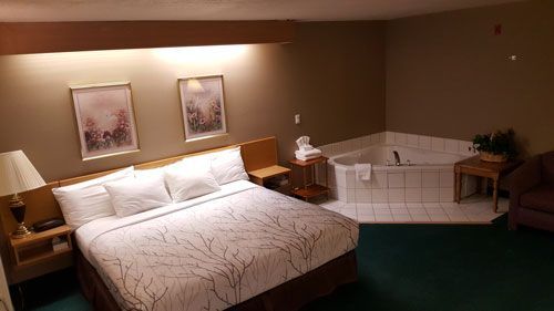 A hotel room with a king size bed and a jacuzzi tub.
