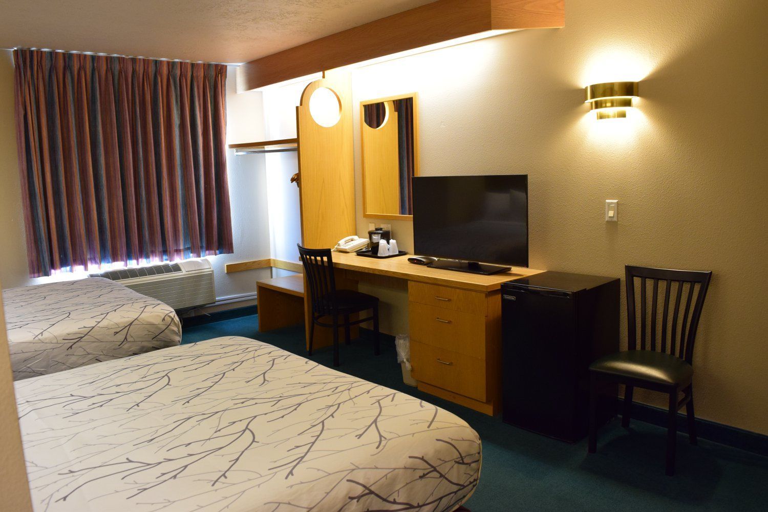 A hotel room with two beds and a flat screen tv