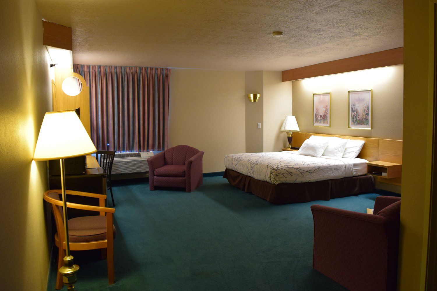A hotel room with a king size bed and chairs