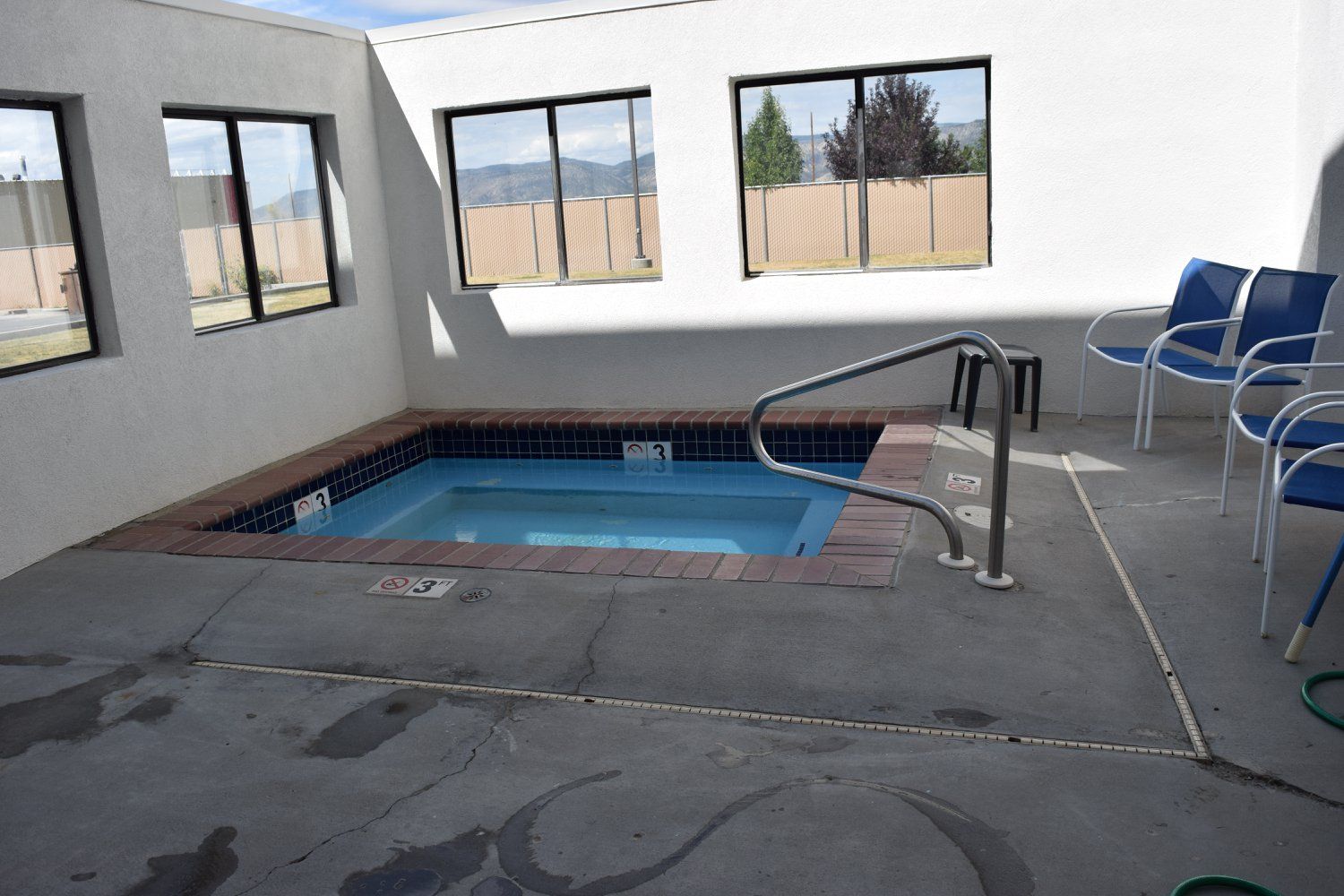 A swimming pool in a room with chairs and windows