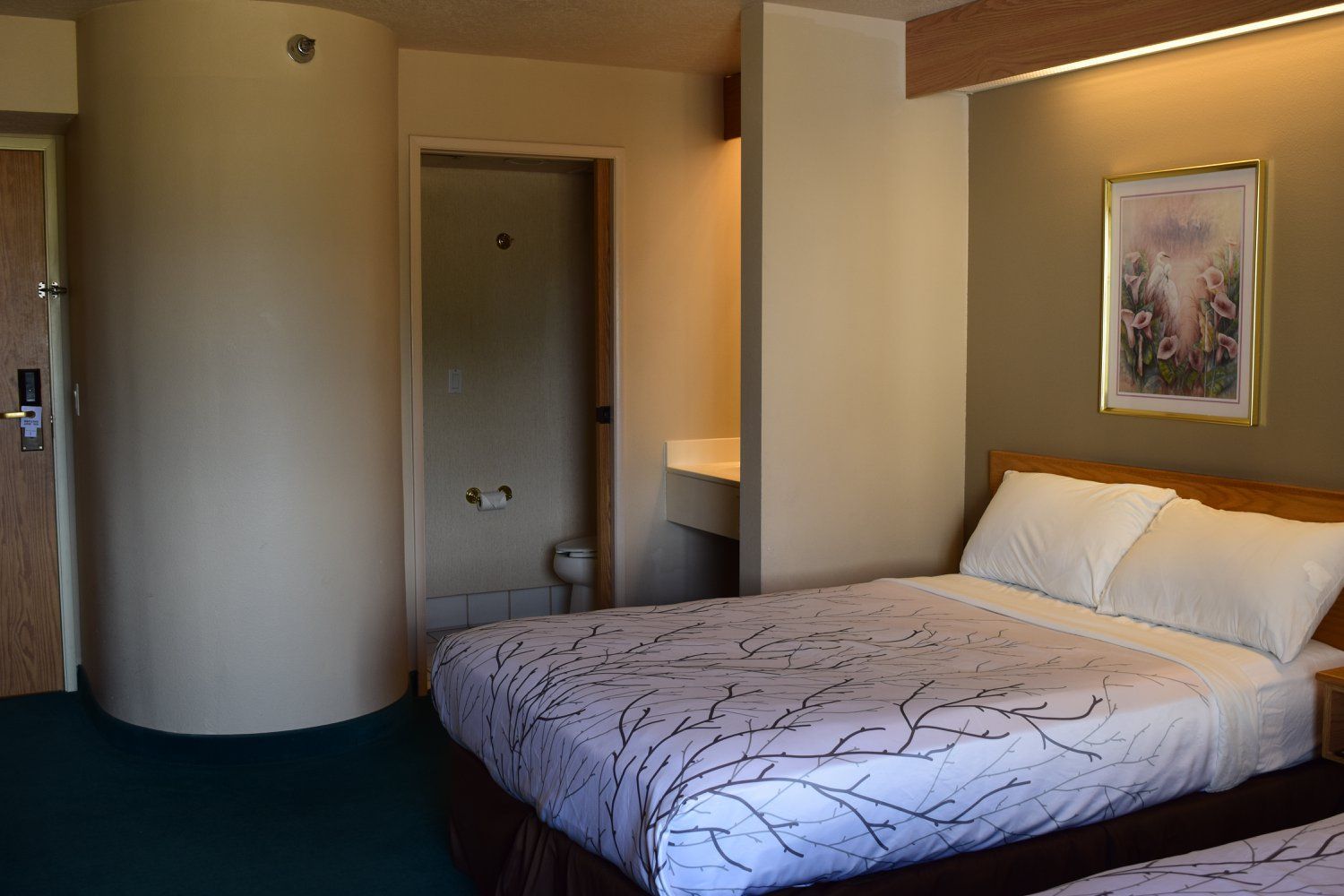 A hotel room with two beds and a picture on the wall.