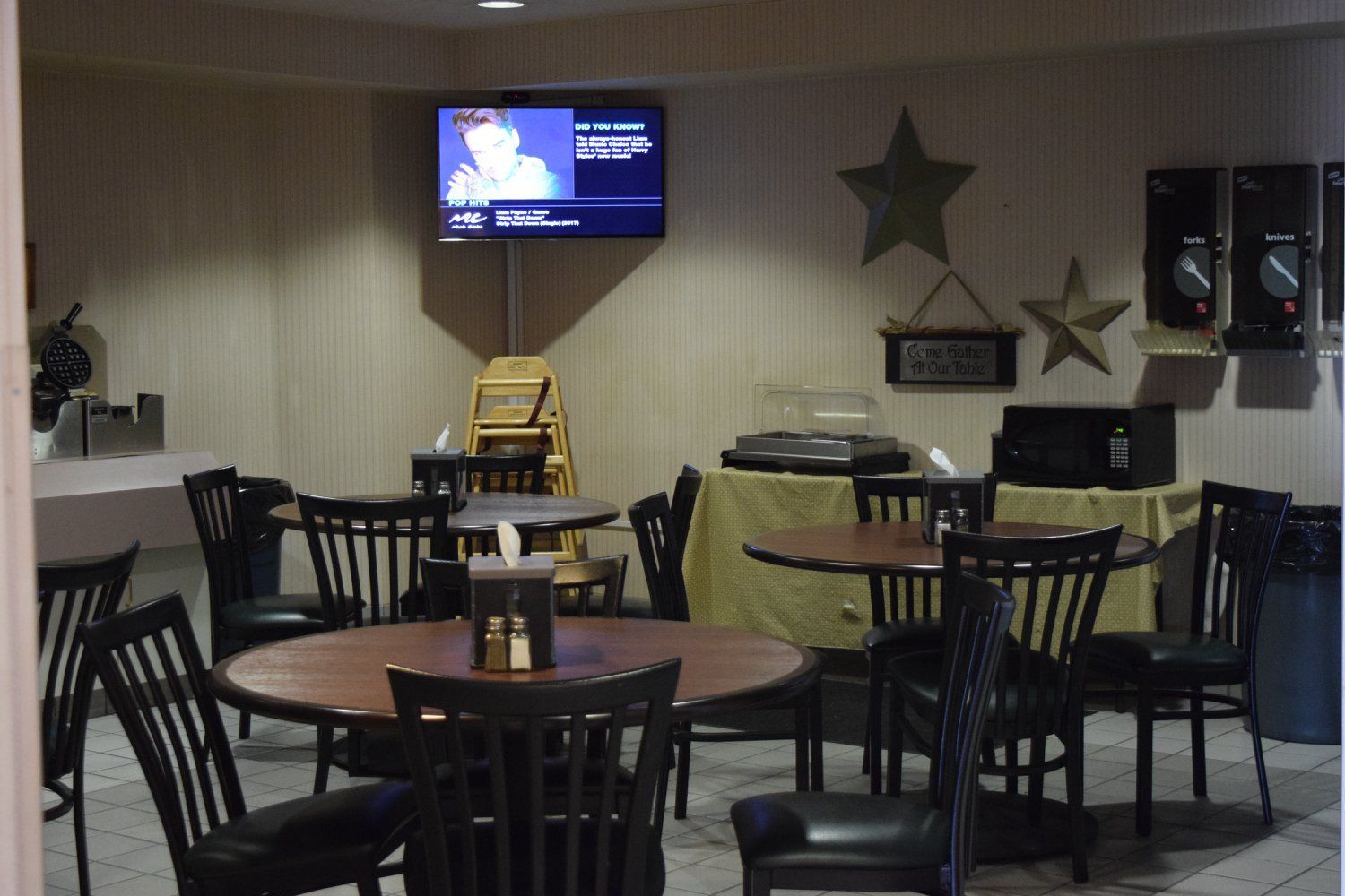 A restaurant with tables and chairs and a flat screen tv