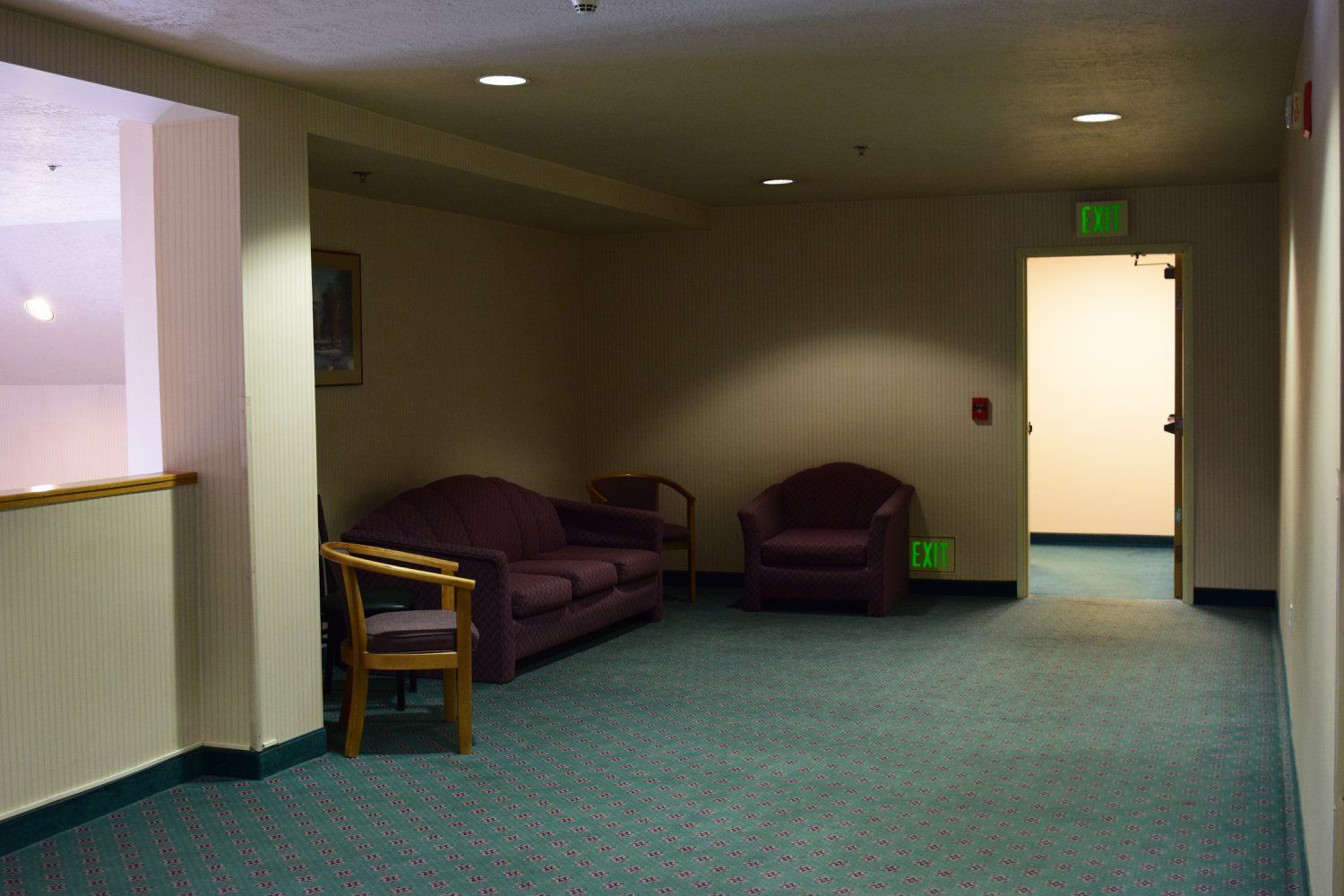 A hallway with a green exit sign on the wall