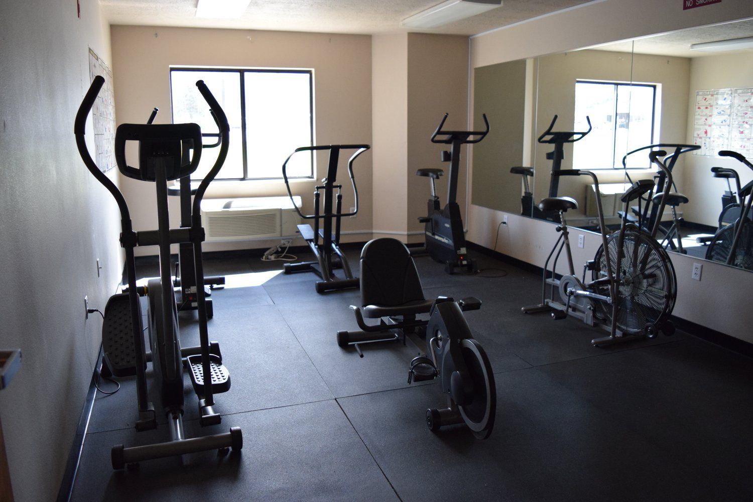 A gym with a lot of exercise equipment and a large mirror.