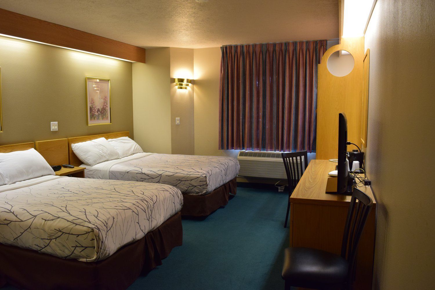 A hotel room with two beds , a desk and a television.