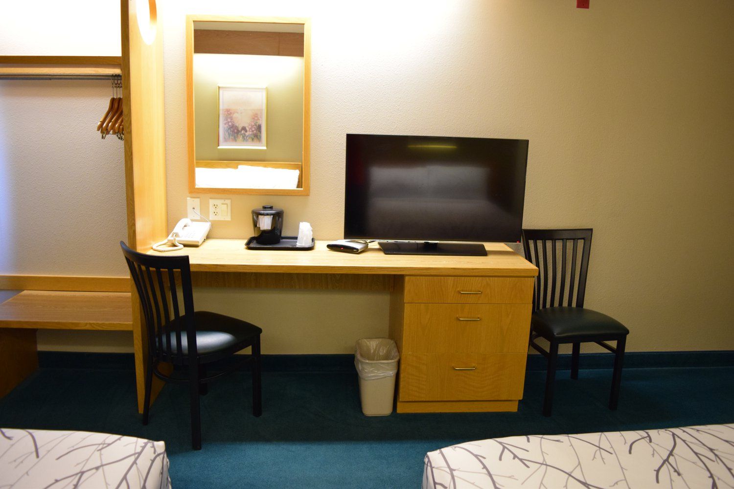 A hotel room with two beds a desk and a flat screen tv