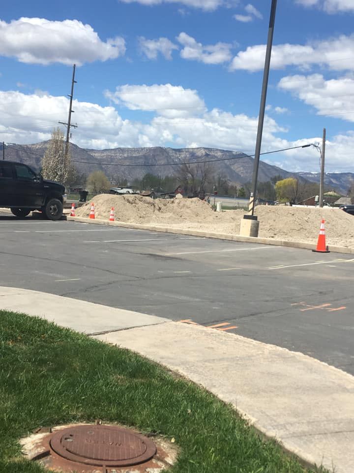A black truck is parked on the side of the road next to a manhole cover.
