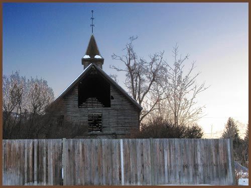A church behind a wooden fence with trees in the background