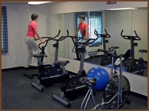 A woman is riding an exercise bike in a gym